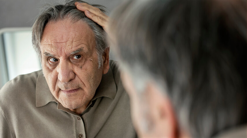 old man looking at himself in mirror not recognising himself